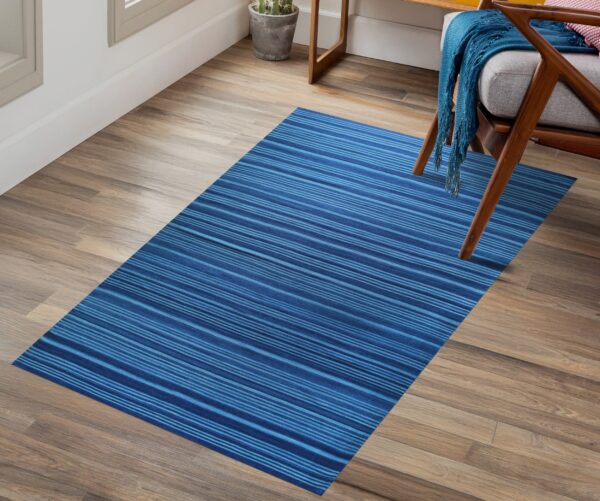 Blue striped rug on wood plank flooring next to a mid-century style wooden chair with a gray cushion.