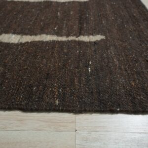 Dark brown speckled rug featuring tan horizontal stripes on light plank wood flooring.