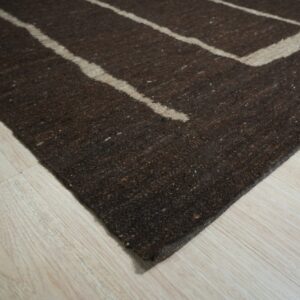 Dark brown textured rug featuring thick tan geometric stripes resting on light wood flooring.