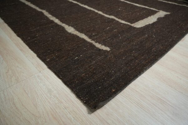 Dark brown textured rug featuring thick tan geometric stripes resting on light wood flooring.