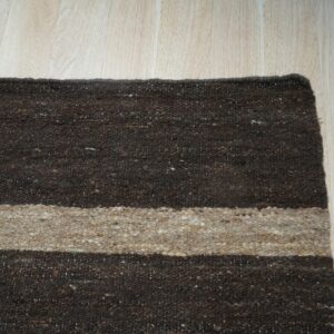 Coarse brown and beige striped rug lying on light plank wood flooring.