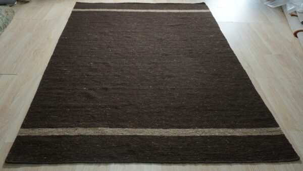 Rectangular dark brown, low-pile rug featuring light tan stripes on pale wood plank flooring.