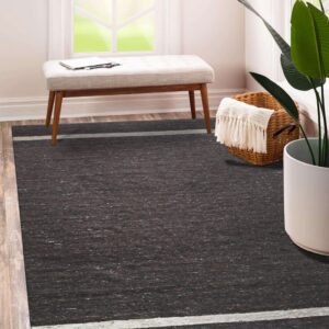 Speckled dark brown rug with thin gray stripes sits on wood flooring next to a bench and houseplant.