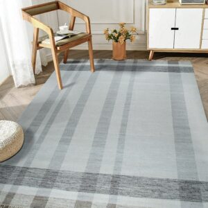 A flatwoven gray and blue striped rug with a visible chevron weave sits on herringbone wood flooring.