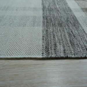 Herringbone and knubby textured stripes in gray and cream natural fibers lie on light wood planks.