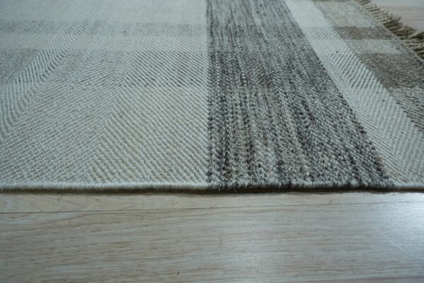 Herringbone and knubby textured stripes in gray and cream natural fibers lie on light wood planks.