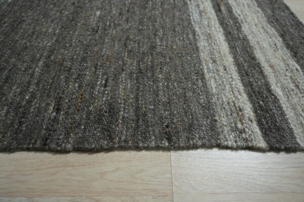Chunky low-pile rug with vertical stripes in mixed shades of gray and natural beige on light wood.
