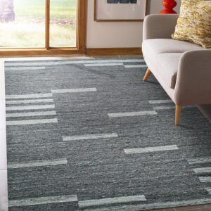 Dark gray rug with light gray geometric linear patterns lies next to a beige sofa by a window.