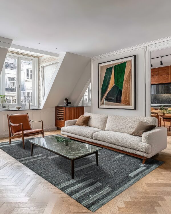 Dark gray abstract rug on a herringbone floor anchors a modern living room with a cream sofa.