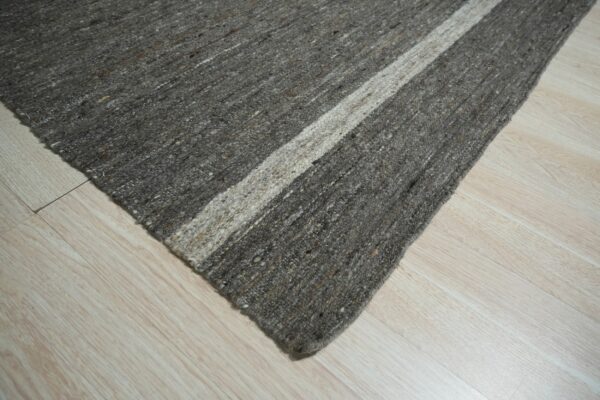 Mottled gray texture rug corner featuring a broad cream stripe on light wood plank flooring.