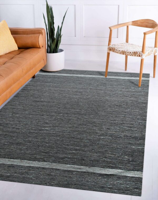 Textured dark gray area rug with pale gray stripes in a room featuring a leather sofa and wood chair.