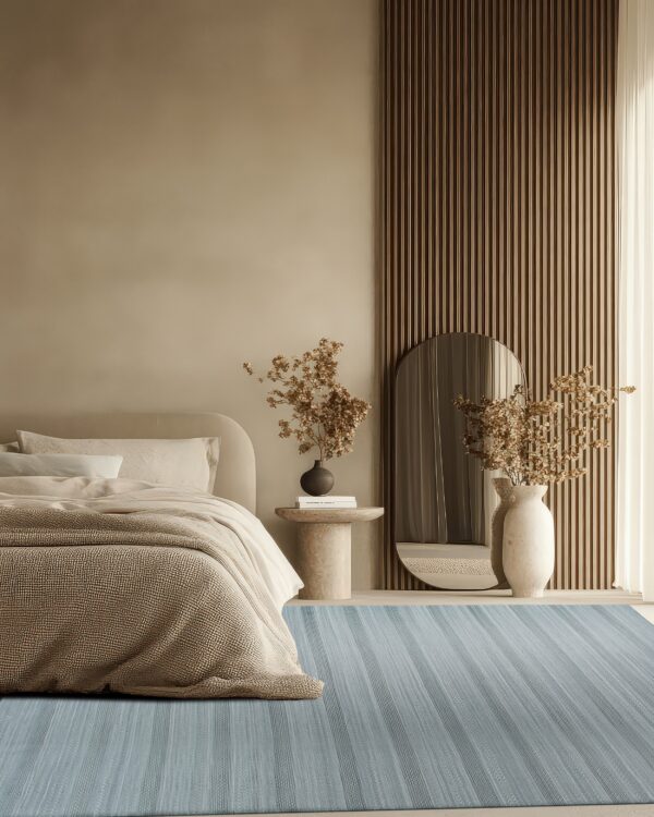 A dusty blue striped rug anchors a serene bedroom with beige walls and textured wood paneling.