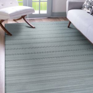A low-pile blue-gray rug with detailed horizontal geometric stripes covers wood flooring near modern seating.