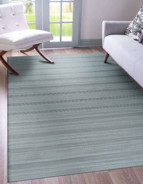 A low-pile blue-gray rug with detailed horizontal geometric stripes covers wood flooring near modern seating.