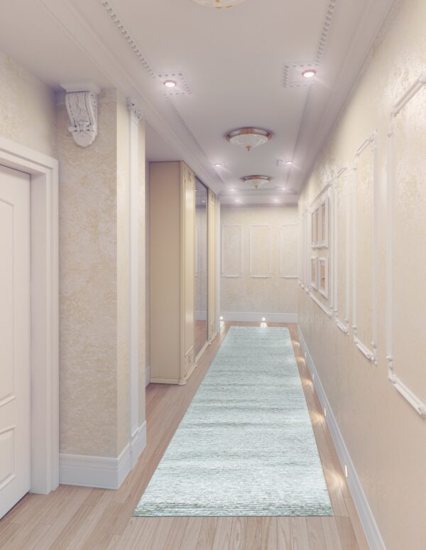 A textured light blue runner rug spans a long, bright hallway with wood floors and ornate molding.