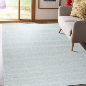 A light blue textured rug lies on the floor next to a neutral sofa in a brightly lit room.