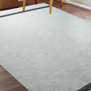 Light gray low-profile rug with black lines on dark wood floors near a wooden chair leg.