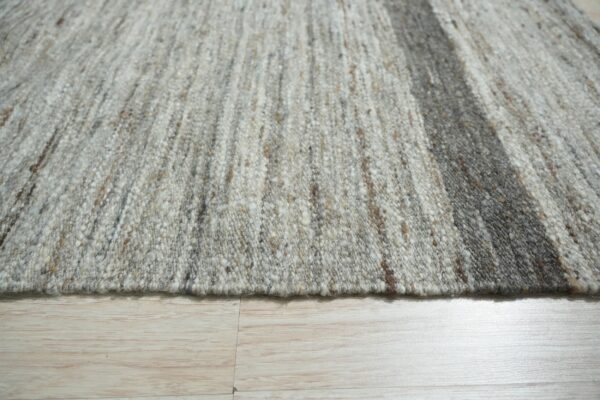 Chunky gray and off-white woven rug texture featuring a wide dark vertical stripe on light wood floor.