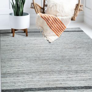 Textured light gray rug featuring a dark stripe, placed on a white floor near a potted plant and wicker chair.
