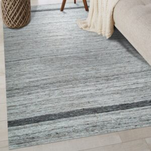 The textured gray area rug with horizontal striations and a dark band lies beneath a beige couch.