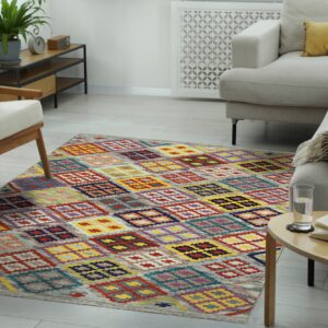 A colorful geometric diamond pattern rug sits on light wood flooring in a modern living room.