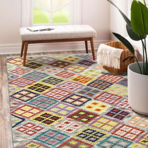 A vibrant rug with multicolor geometric diamonds covers a wood floor beside a white bench.
