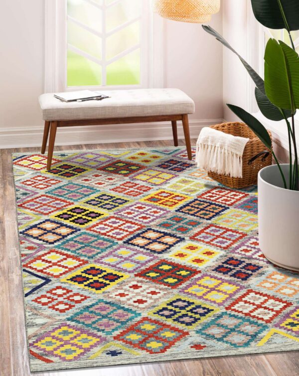 A vibrant rug with multicolor geometric diamonds covers a wood floor beside a white bench.
