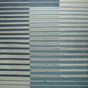 The rug features geometric horizontal stripes in dark blue, aqua, and off-white color blocks.