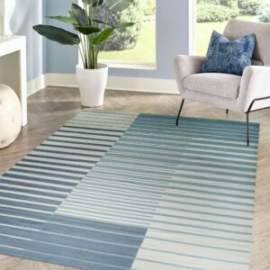 Diagonal color-blocked rug with fading horizontal blue and white stripes on herringbone wood flooring.
