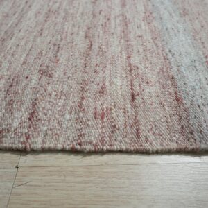 Chunky woven rug featuring a variegated white and reddish-brown speckled texture on light wood planks.
