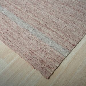 Speckled pink and cream flatweave rug with a light gray stripe shown on light wood floors.