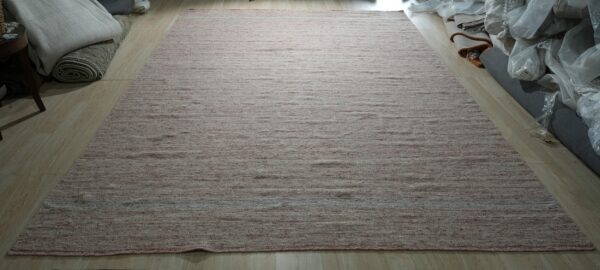 Textured, low-pile rug featuring dusty rose and cream horizontal striations on light wood flooring.