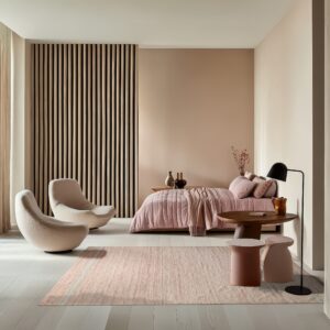 A dusty rose textured rug anchors a modern bedroom featuring light wood floors and pink accent furniture.