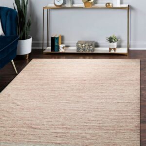A large, heathered pink and cream rug lies on dark hardwood floors, near a blue velvet chair and console table.