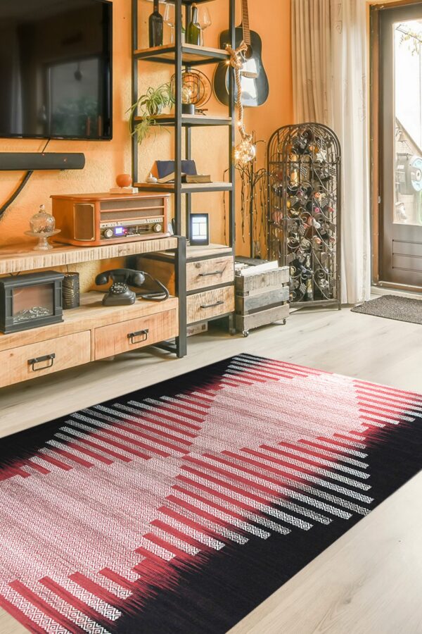 Black, red, and white geometric flatweave rug on light wood flooring beneath an industrial shelf unit.