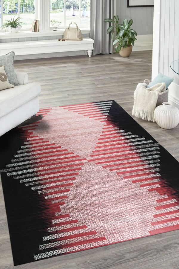 Black, red, and white woven rug with a central geometric pattern sits on light wood flooring.
