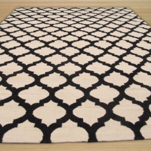 A black and cream rug featuring a repeating geometric lattice pattern on light wood flooring.