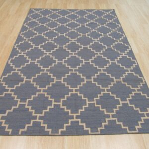 Blue flatweave rug with a beige repeating geometric trellis diamond pattern on light wood floor.