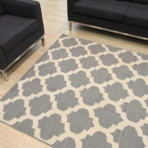 Gray and beige quatrefoil rug on wood flooring with dark gray modern armchair and sofa.