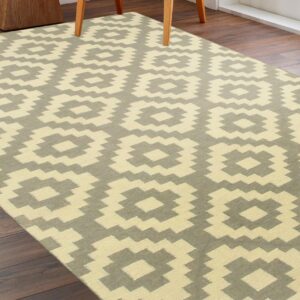 Pale yellow and gray flatweave rug with large stepped medallions on dark wood floors.
