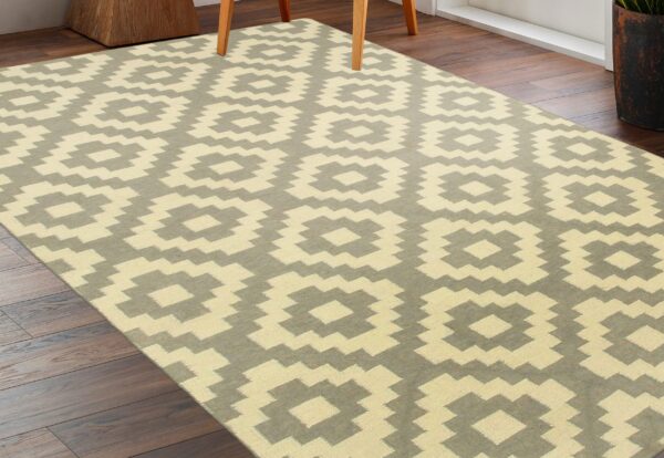 Pale yellow and gray flatweave rug with large stepped medallions on dark wood floors.