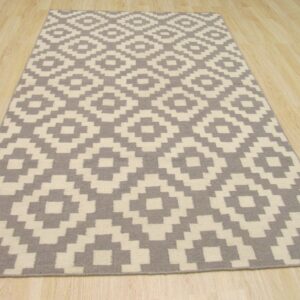 Rectangular rug with a gray and cream geometric diamond pattern placed over light wood flooring.