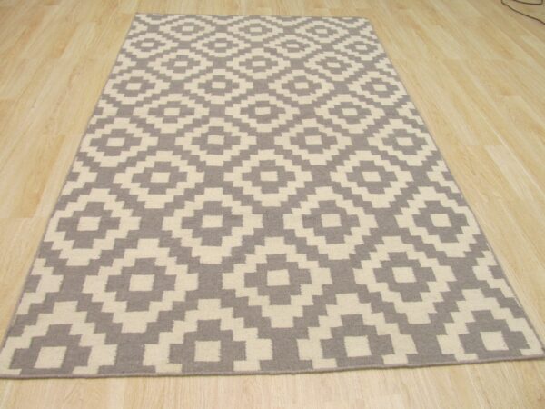 Rectangular rug with a gray and cream geometric diamond pattern placed over light wood flooring.
