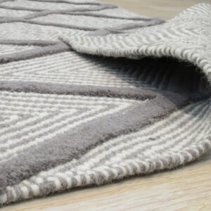 Close-up of a rolled gray rug featuring raised geometric lines on a textured striped weave on light wood.