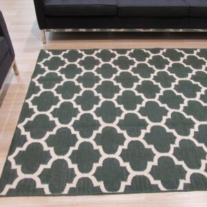 Dark green and beige quatrefoil rug on light wood floor next to dark gray modern furniture.