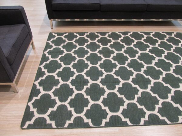 Dark green and beige quatrefoil rug on light wood floor next to dark gray modern furniture.