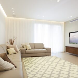 A low-pile, light beige and gray trellis rug anchors a modern living room with a neutral sectional sofa.