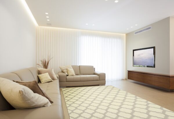 A low-pile, light beige and gray trellis rug anchors a modern living room with a neutral sectional sofa.