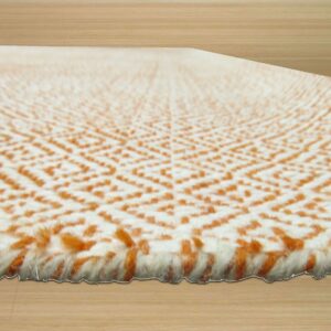 High-pile cream and terracotta rug with a textured geometric pattern rests on light wood planks.