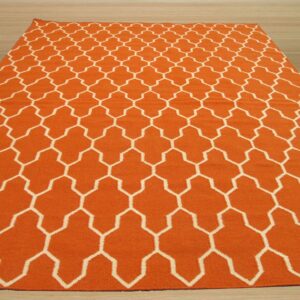 Orange low-pile rug with a repeating white geometric lattice pattern is displayed on light wood planks.